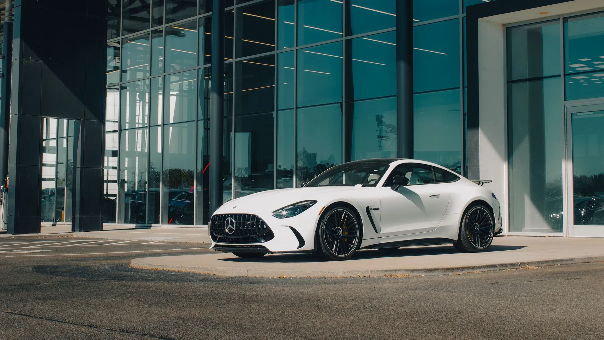 Mercedes-AMG GT màu trắng đỗ trước tòa nhà kính ngày nắng