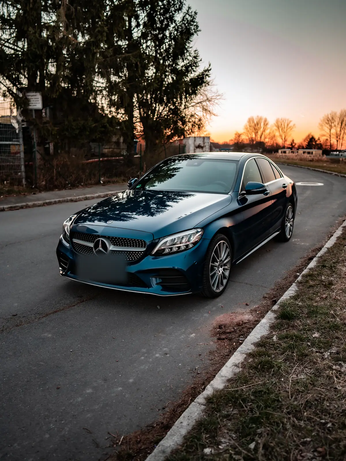 Mercedes C-Class sedan xanh đậm đỗ bên đường lúc hoàng hôn