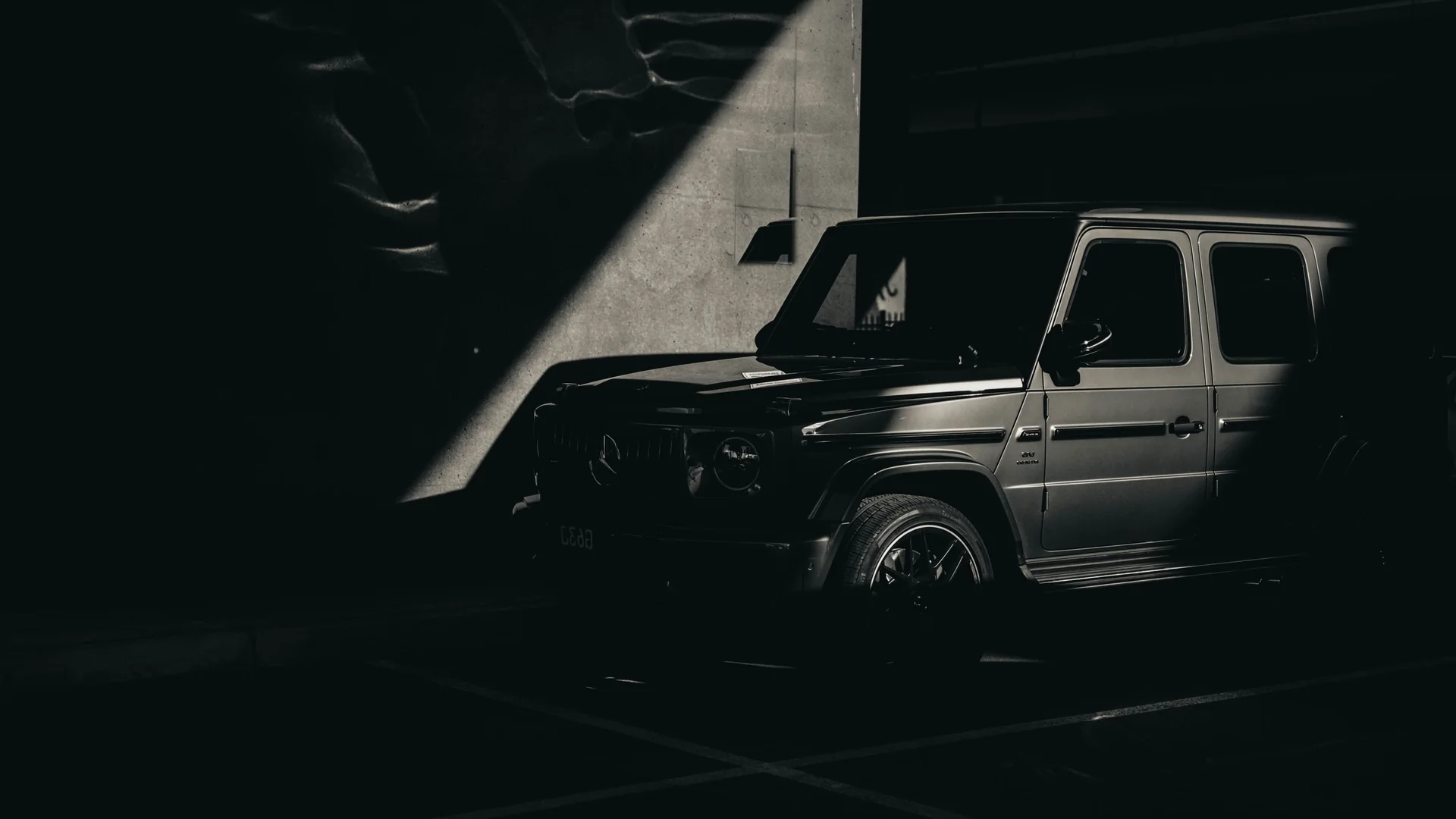 Mercedes G-Class màu đen trong hầm bê tông tối với vệt nắng chéo